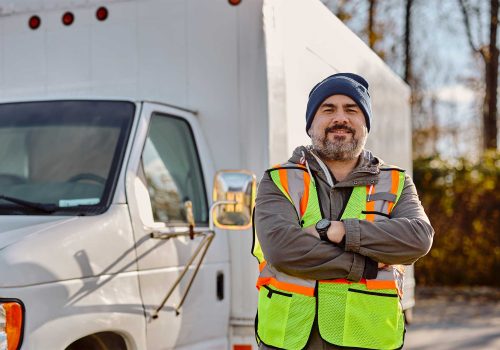 smiling-truck-driver-with-arms-crossed-on-parking-2023-11-27-04-56-27-utc.jpg